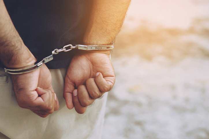 Prisoner male criminal standing in handcuffs with hands behind back. banner copy space.